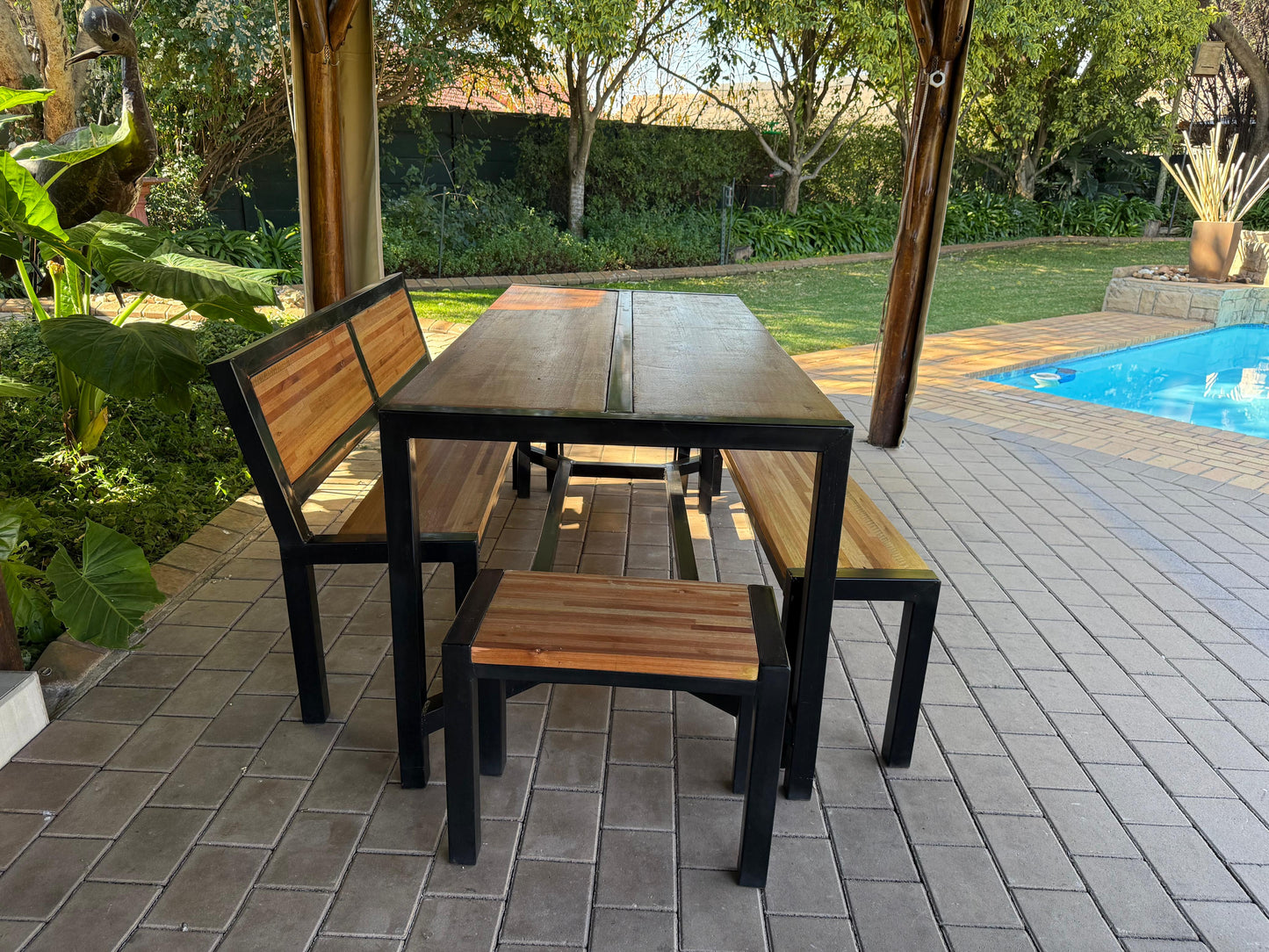 Outdoor dining set with table and benches on a patio near a pool