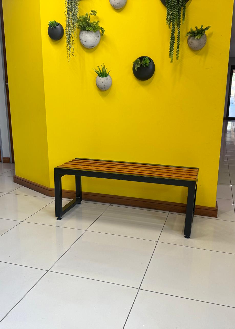 Wooden bench in front of a yellow wall with decorative planters.
